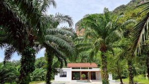 A modern house with a red roof, surrounded by lush greenery and palm trees. - Red Cheek Mountain Villa  (Krabi)