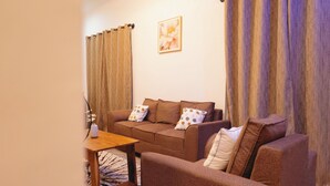 A living room with a brown sofa, a wooden coffee table, and a patterned rug. - Freedomhomesairbnb (Arusha)