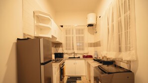 A compact kitchen with a refrigerator, stove, microwave, and sink. - Freedomhomesairbnb (Arusha)