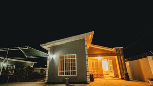 A modern house with a covered patio, a visible window, and a door leading to an interior space. - Freedomhomesairbnb (Arusha)