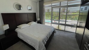 A modern hotel room with a large bed, two bedside tables, a wardrobe, and a window with blinds. - Feel at home in paradise/ A few minutes from the beach. (Nuevo Vallarta)