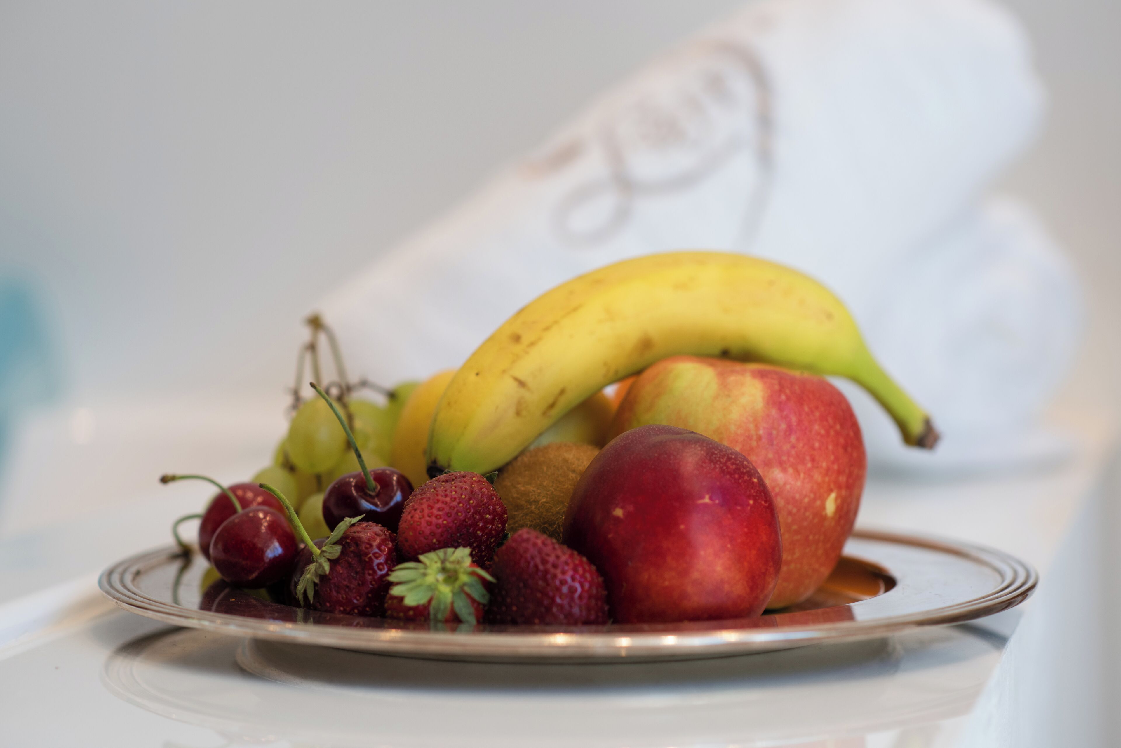 Un plato de fruta con plátanos, manzanas y fresas.