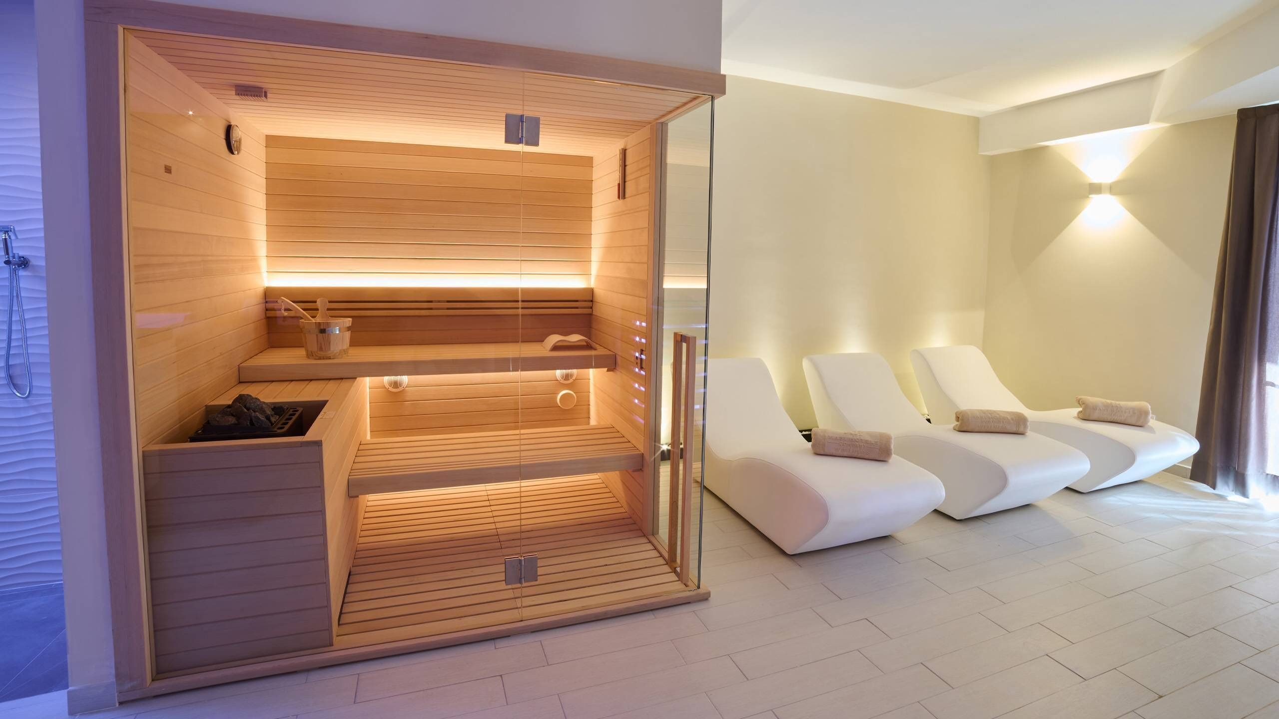 Een moderne spa ruimte met houten sauna's, een ruimte voor massages en een douche.