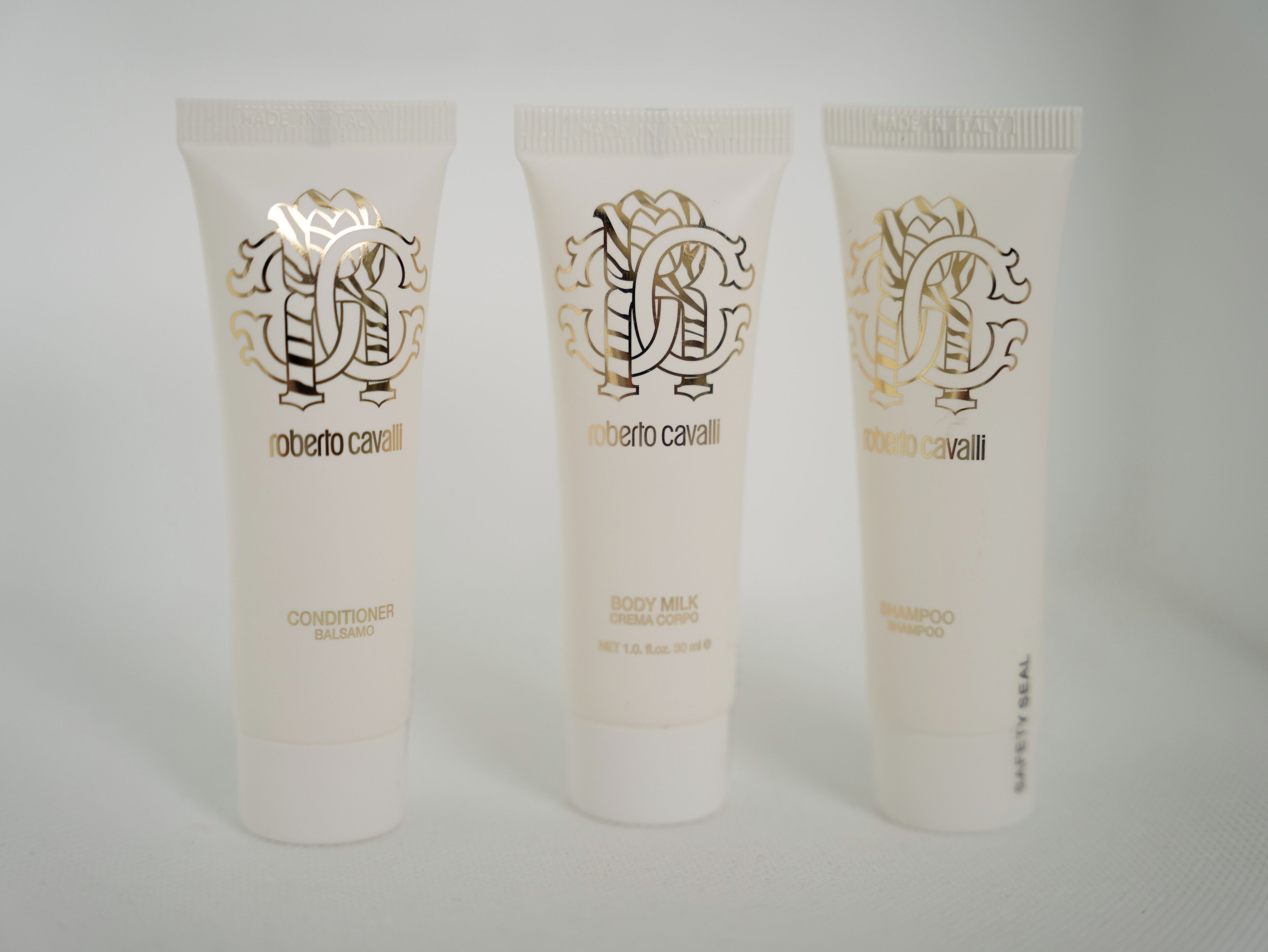 Three tubes of Roberto Cavalli products: conditioner, body milk, and shampoo.