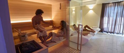 A modern spa room with wooden paneling, a glass partition, and a relaxation area with a sofa.