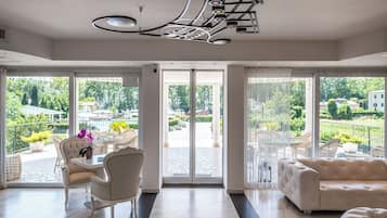Una habitación amplia con un gran ventanal, un sofá blanco, una mesa de comedor con sillas y un moderno lámpara de techo.