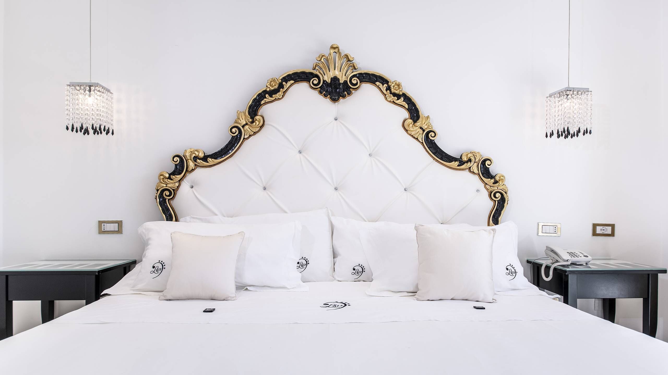 A bedroom with a tufted headboard, white bedding, and two bedside tables with lamps.