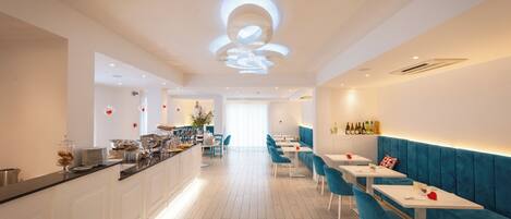 A modern restaurant with a long counter, blue chairs, and white tables.