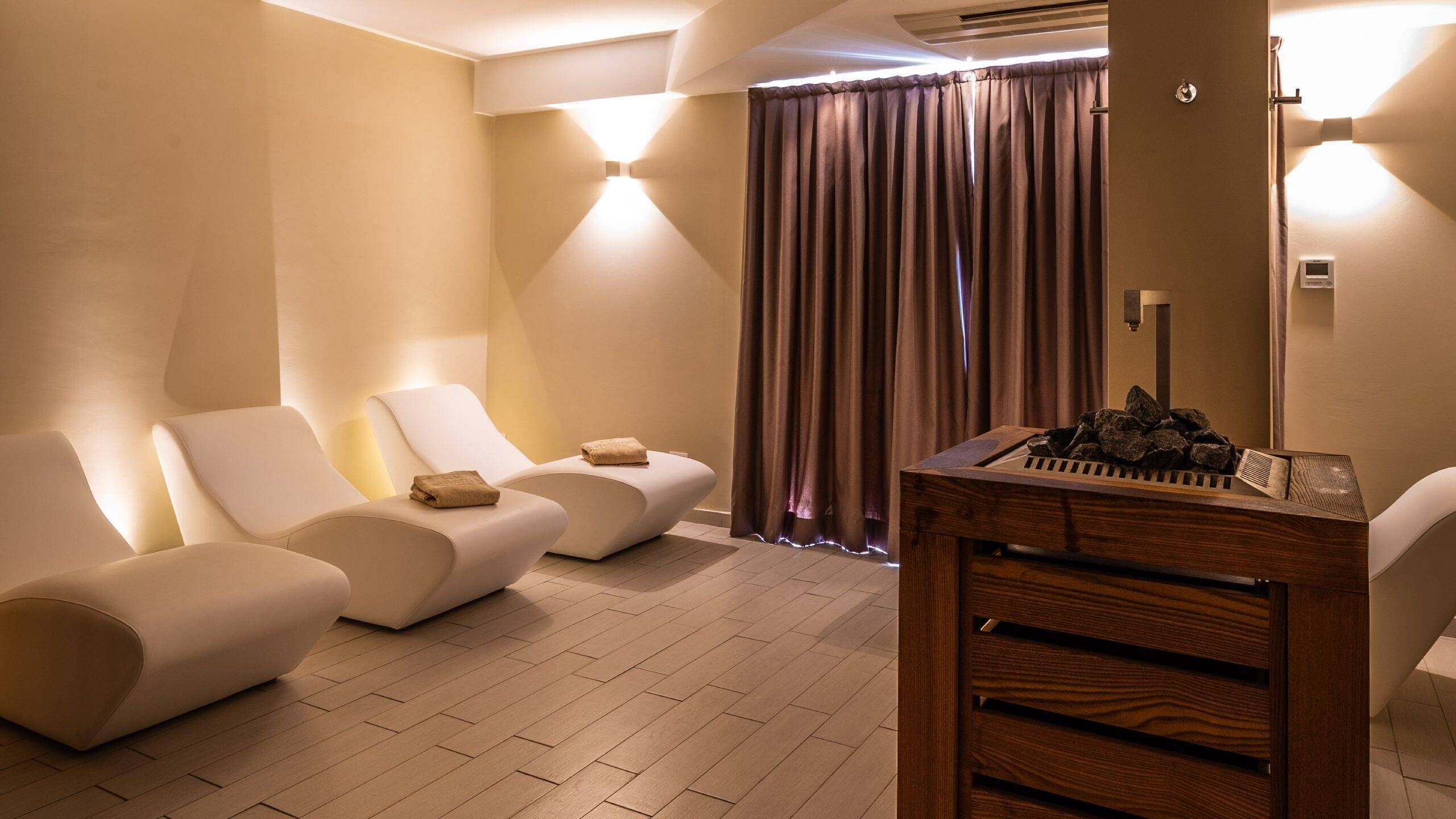 Een spa-ruimte met drie ligstoelen, een houten tafel met een toetsenbord en een gordijn.