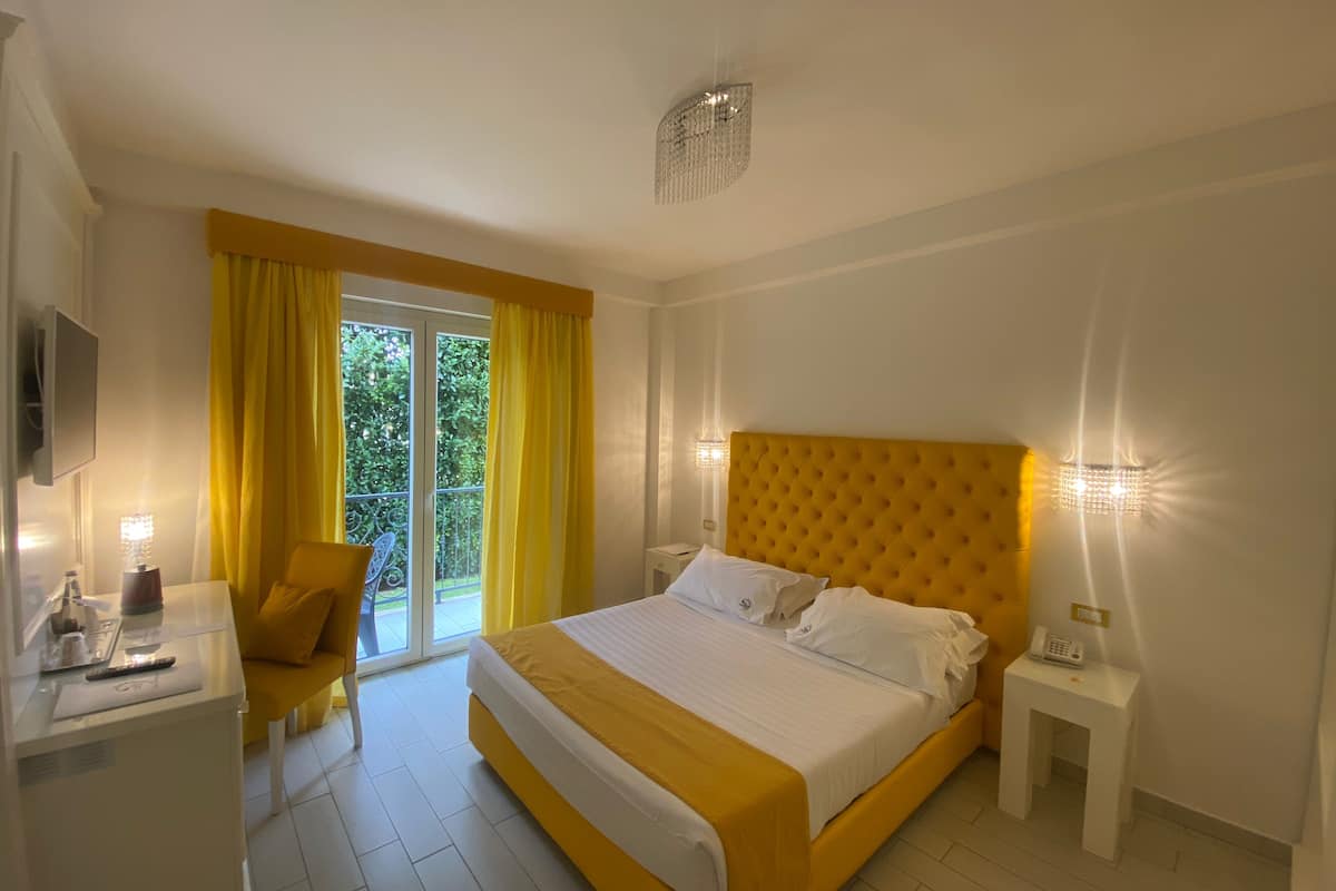 Habitación de hotel con una cama grande, un escritorio con una silla, una mesita de noche y un televisor.
