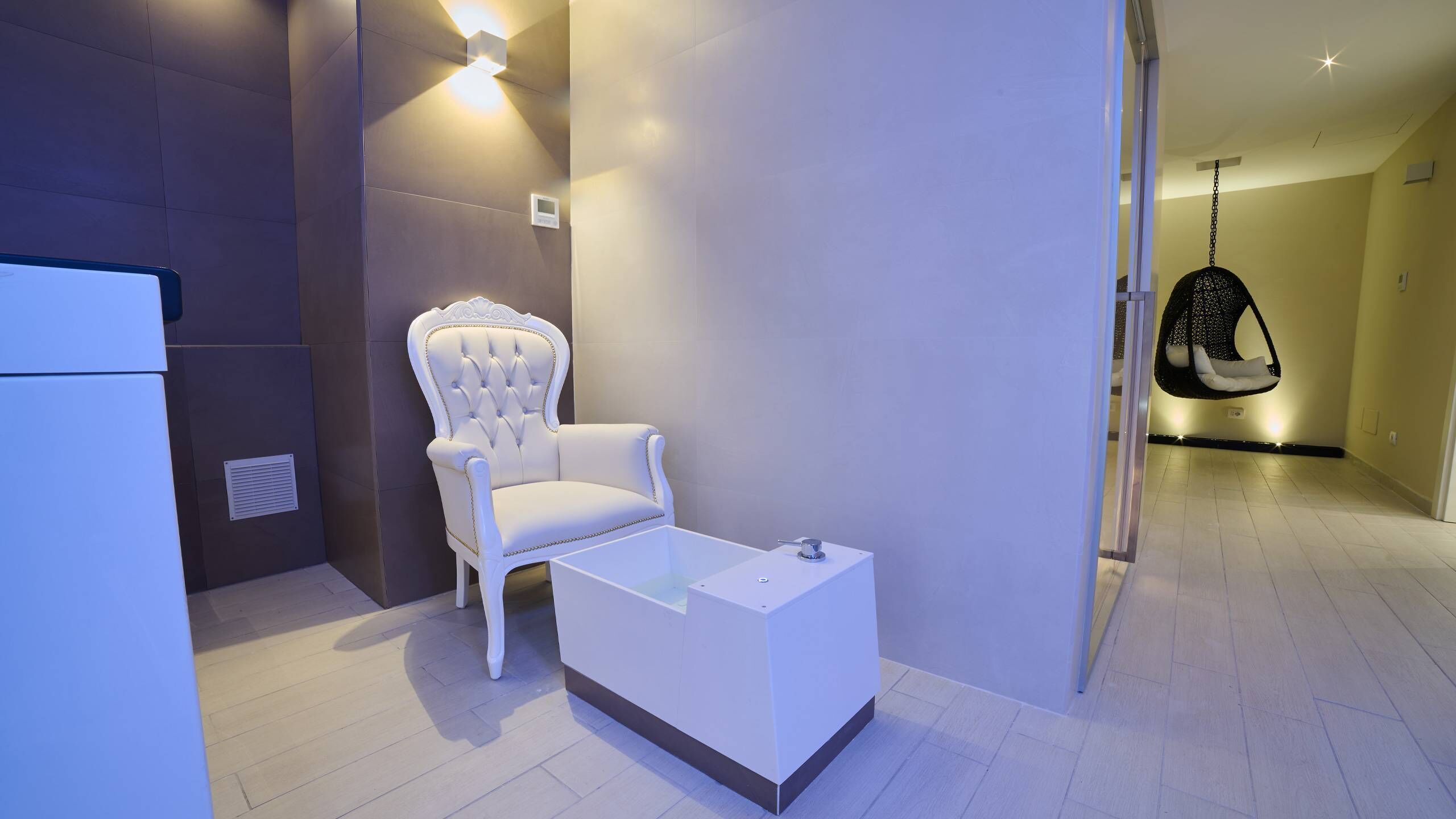 A modern bathroom with a white chair, a white sink, and a hanging chair.
