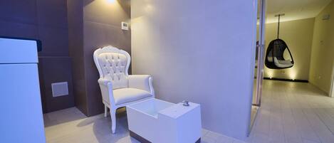 A modern bathroom with a white chair, a white sink, and a hanging chair.