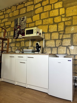 Een keuken met een stenen muur, een magnetron, een spoelbak en een vaatwasser.