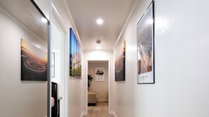 Un couloir doté d’un parquet en bois clair, de murs blancs et d’œuvres d’art encadrées.