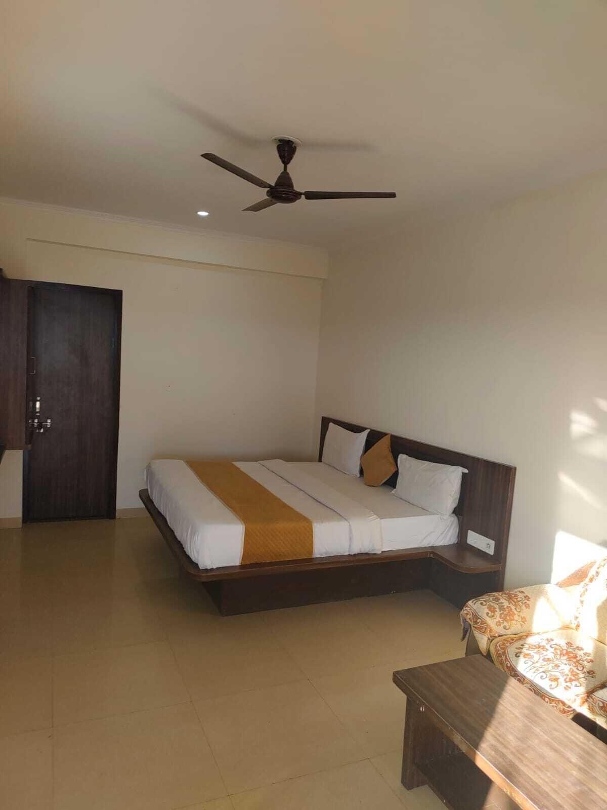 A bedroom with a bed, a ceiling fan, a wardrobe, and a small table.