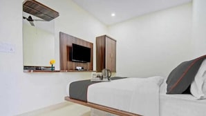 A modern bedroom with a bed, a television, a wardrobe, and a small table with a flower vase. - The Experia  Boutique hotel  (Jaipur)