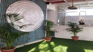 A room with a patterned wall, a large circular decorative item, and potted plants. - The Experia  Boutique hotel  (Jaipur)