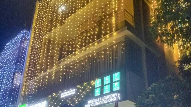A building with multiple floors, adorned with string lights. There are signs for a laundry service and a boutique hotel. - The Experia  Boutique hotel  (Jaipur)