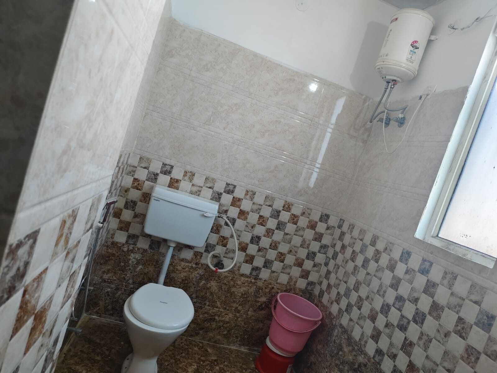 A bathroom with a toilet, a water heater, and a checkered tile backsplash.