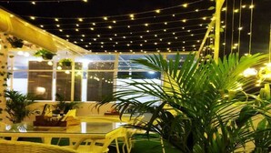 An outdoor dining area with string lights, wicker furniture, and potted plants. - The Experia  Boutique hotel  (Jaipur)