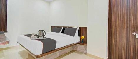 A modern hotel room with a bed, a nightstand, a ceiling fan, and a wooden door.