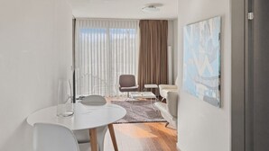 A modern room with a round table, two chairs, a sofa, a coffee table, and a painting on the wall. - Comfortable 1BR flat / great location - Baron 44 (Zürich)