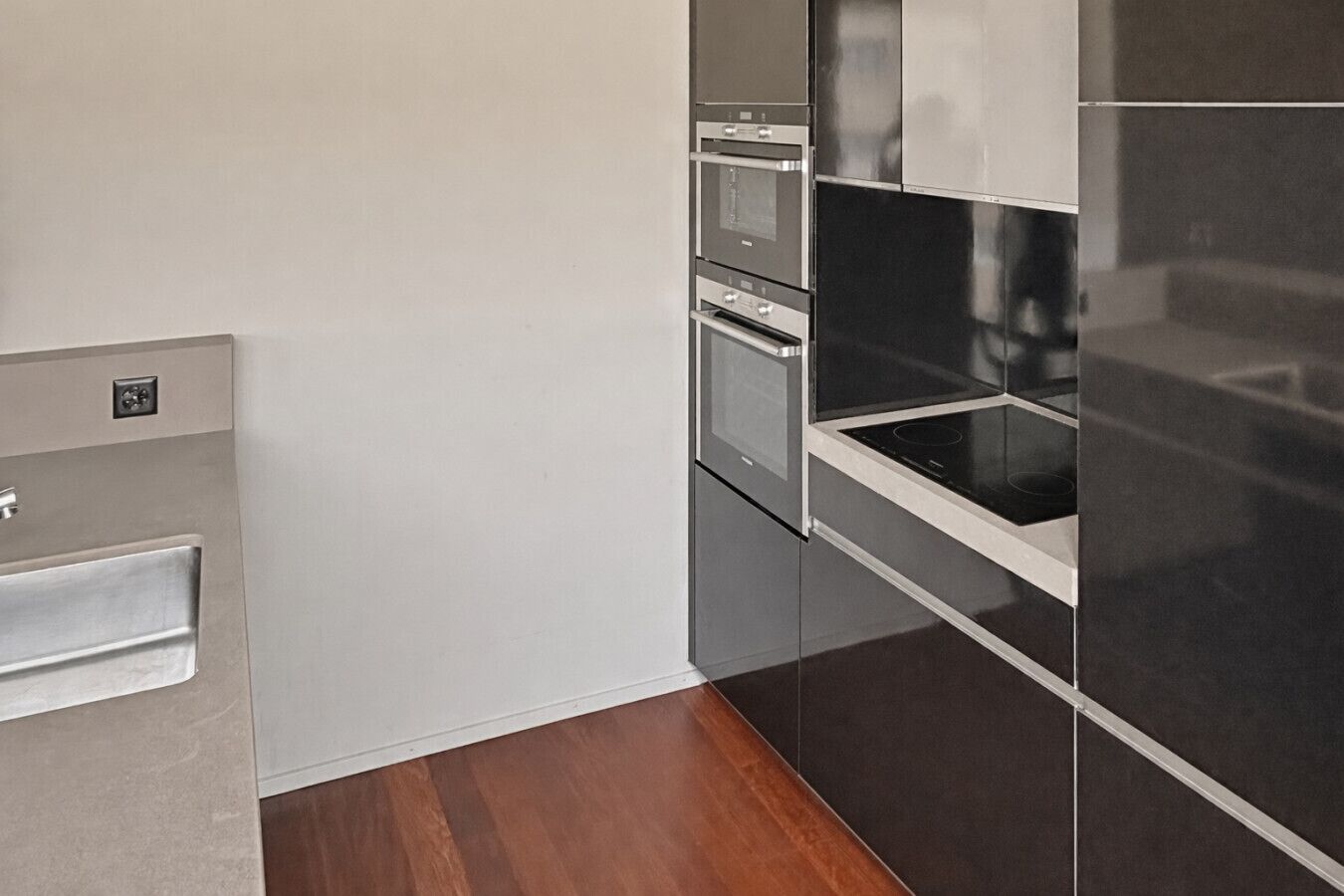 A modern kitchen with stainless steel appliances, a built-in oven, and a sleek black countertop.