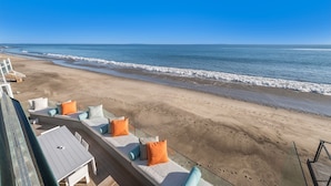 Eine Terrasse direkt am Strand mit Sitzgelegenheiten und Blick aufs Meer.