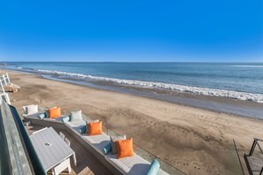 Een terras aan het strand met zitplaatsen buiten en uitzicht op de oceaan.