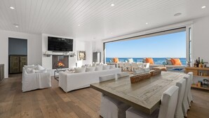 Ein modernes Wohnzimmer mit einem großen Holztisch, weißen Sofas und einem Kamin.