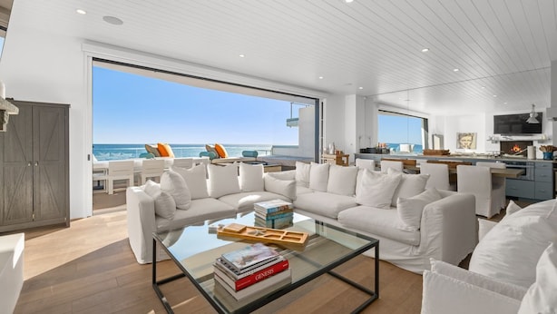 Ein modernes Wohnzimmer mit einem Glastisch, weißen Sofas und Blick auf den Ozean.