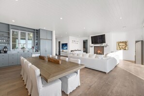 Een moderne keuken met een eethoek, witte meubels en een open haard.