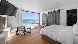 Ein modernes Schlafzimmer mit einem großen Bett, einem Fernseher und einem Balkon mit Meerblick.