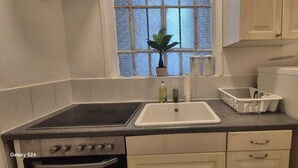A compact kitchen with a stove, sink, and cabinets.