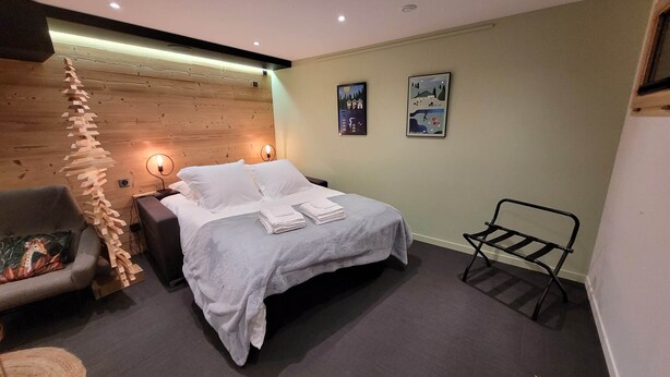 A cozy room with a bed, a chair, and a wall-mounted rack.