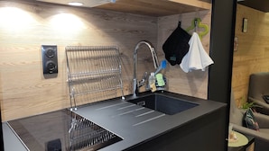 A modern kitchen with a black countertop, stainless steel sink, and a wire rack.