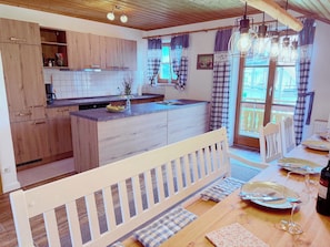 A kitchen with wooden cabinets, a central island, and a dining area with a table set for two.