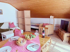 A cozy living room with a dining area, wooden furniture, and a television. - Steibis Country House - Imberg (Oberstaufen)