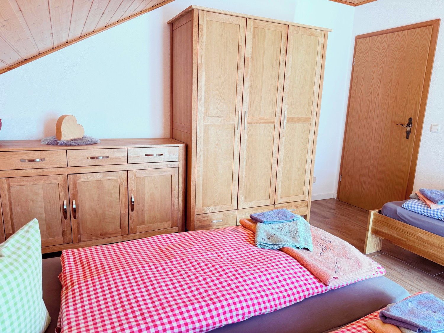 A bedroom with a bed, a wooden wardrobe, and a door.