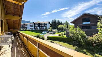 Ein Balkon mit Blick auf eine Wohngegend, darunter ein mehrgeschossiges Gebäude mit Balkonen und ein kleineres Holzhaus.