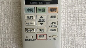A Panasonic air conditioner with a digital display, buttons for temperature control, and a stop function.