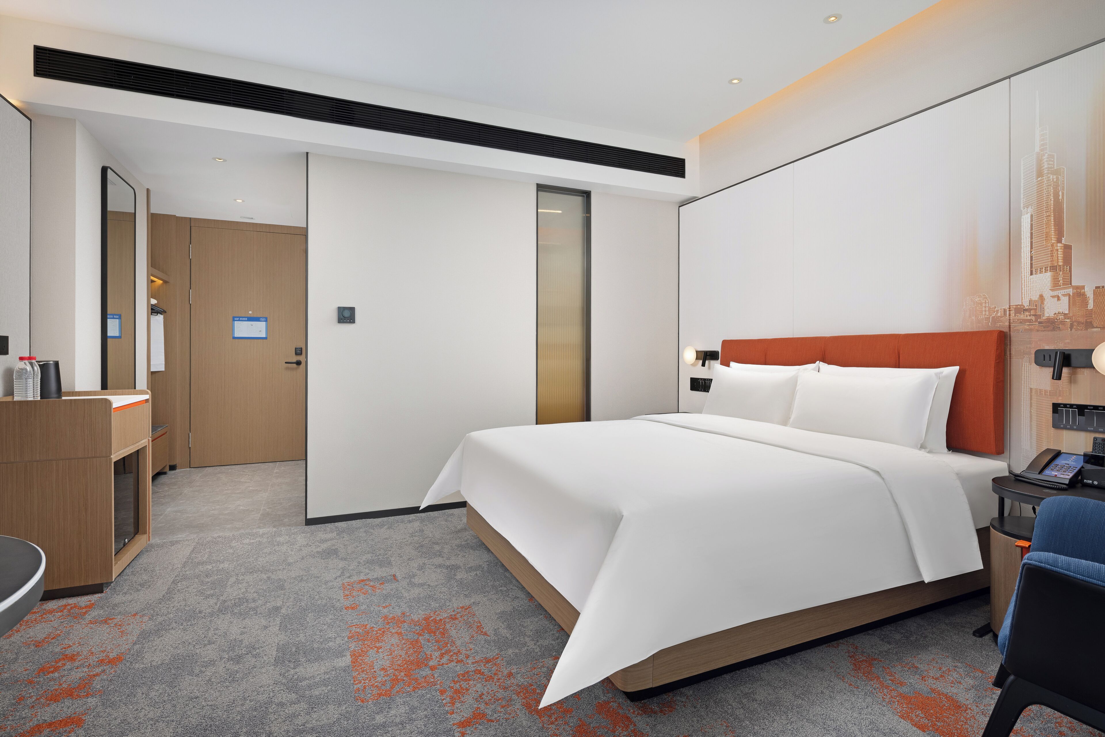 A modern hotel room with a large bed, a desk, and a mirror.