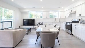 Een moderne keuken met witte kasten, een centraal eiland en een zithoek met een bank en stoelen.
