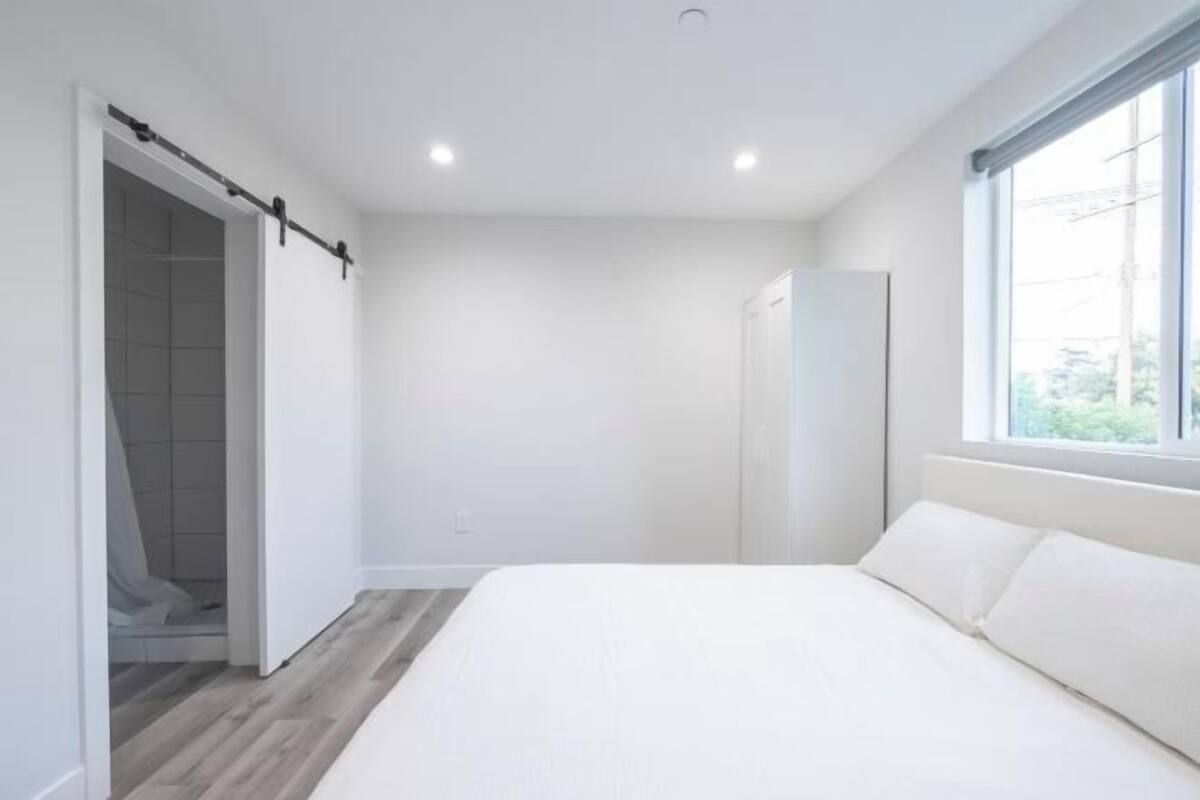Een slaapkamer met een bed, een kledingkast en een raam.