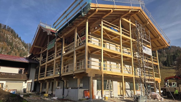 Ein mehrgeschossiges Gebäude im Bau mit sichtbarem Holzgerüst und Gerüst.