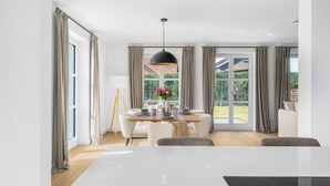 A modern dining area with a large table, chairs, and a hanging light fixture. - Spacious 5-Star Villa with Sauna, Garden and Private Terrace in Tinnum (Tinnum)