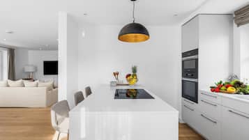 Et moderne køkken med en central ø, et spiseområde med stole og en stue med en sofa.