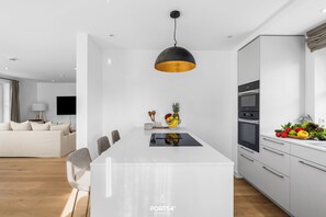Een moderne keuken met een centraal eiland, een eethoek met stoelen en een woonkamer met een bank.