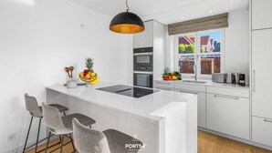 A modern kitchen with white cabinetry, a central island, bar stools, and a hanging pendant light. - Spacious 5-Star Villa with Sauna, Garden and Private Terrace in Tinnum (Tinnum)