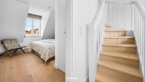 A bedroom with a bed, a chair, a window, and a staircase. - Spacious 5-Star Villa with Sauna, Garden and Private Terrace in Tinnum (Tinnum)